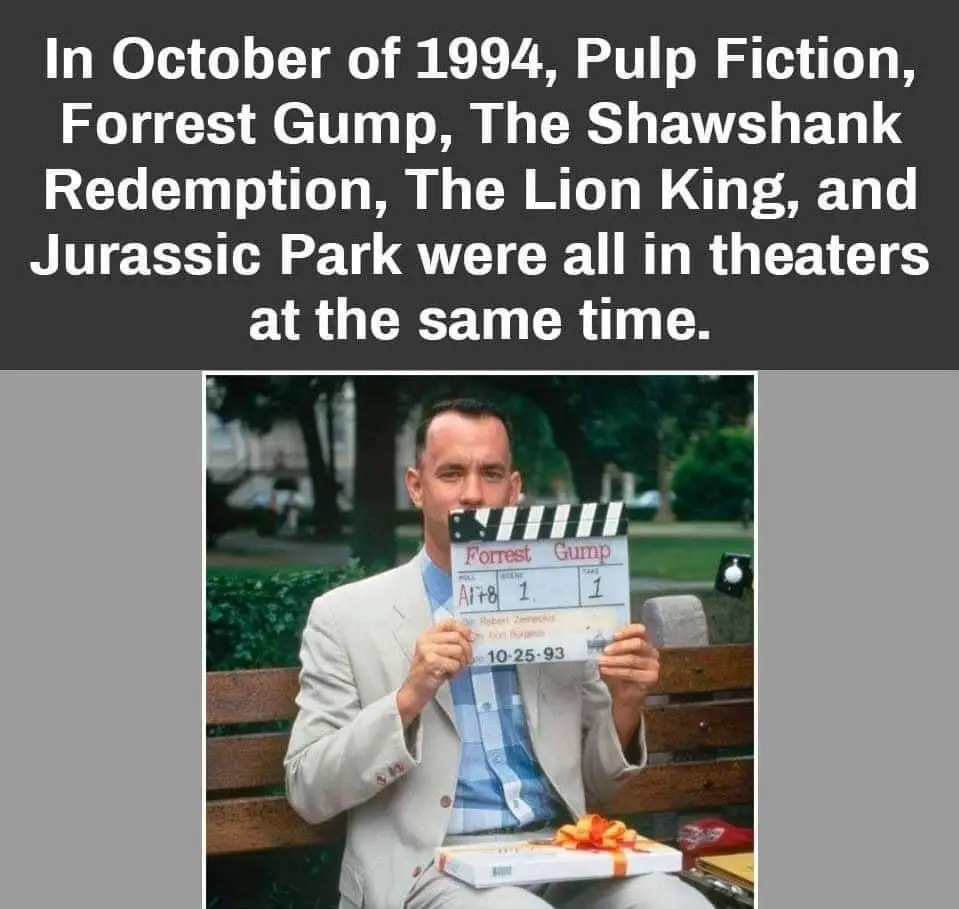 A man, identified as Tom Hanks from the movie 'Forrest Gump', sits on a park bench holding a clapperboard that reads…