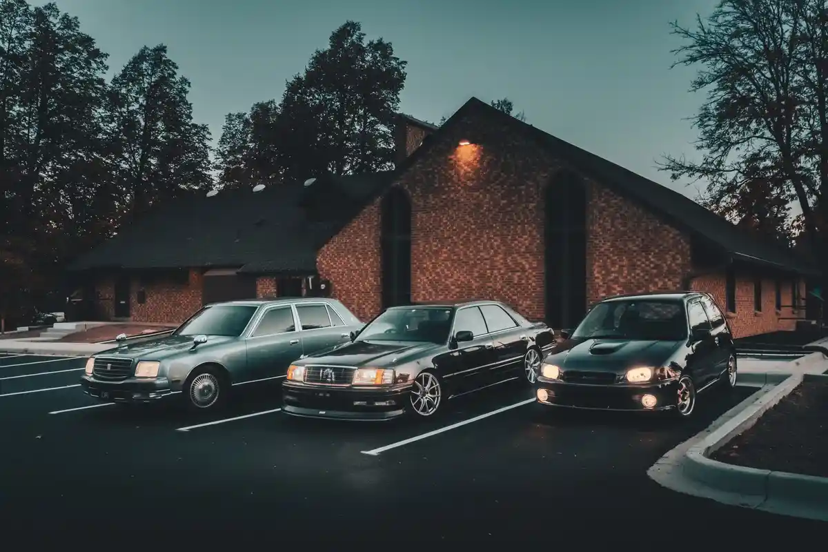 Three Japanese cars—a silver Toyota Century, a black Toyota Celsior, and a black Subaru Impreza—are parked in a lot in front…