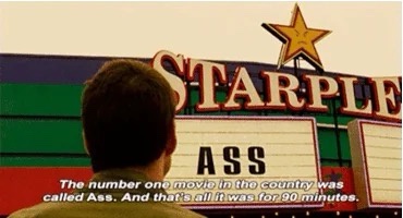A person viewed from behind stands before a movie theater marquee that reads 'STARPLE' with a star above and 'ASS' in large…