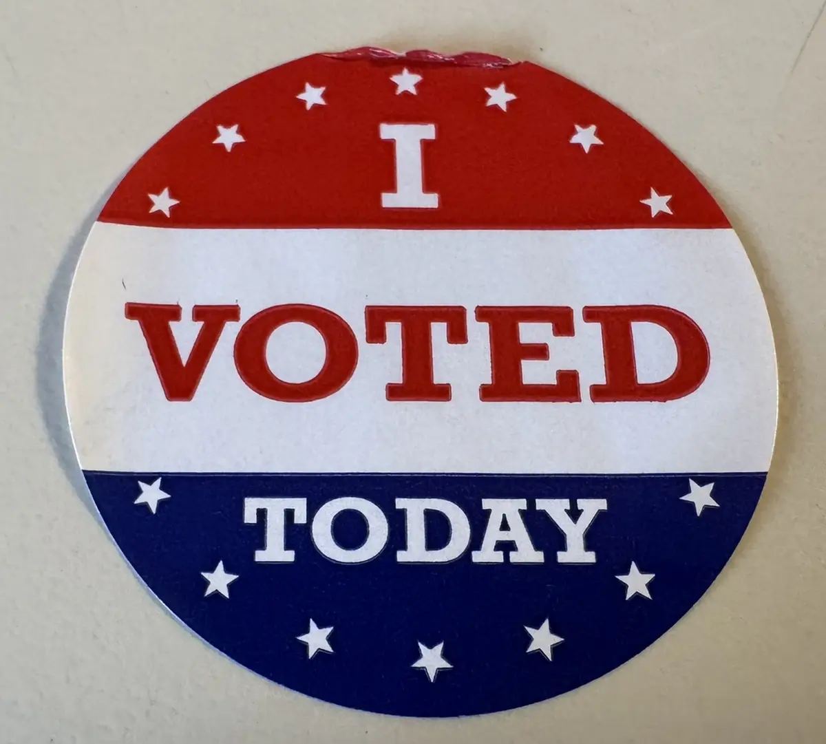 A circular sticker with red, white, and blue horizontal stripes and white stars, displaying the text 'I VOTED TODAY' in bold…