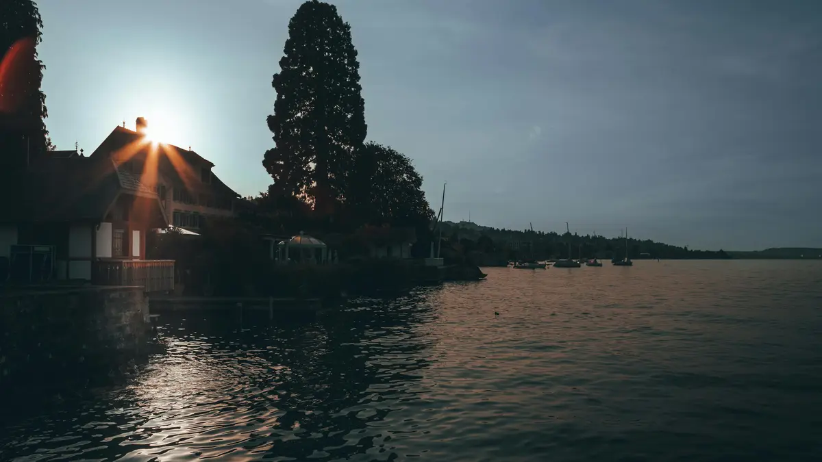 Golden hues dance across the tranquil lake as the sun dips below the horizon, casting a warm glow on the silhouette of a…