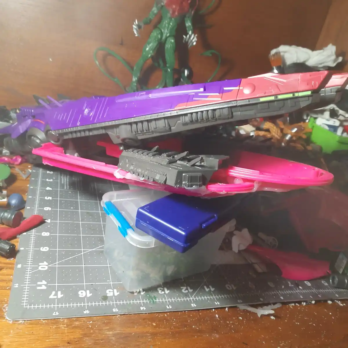 A purple and red toy robot, likely a Transformer, is shown in a partially assembled or disassembled state, balanced…