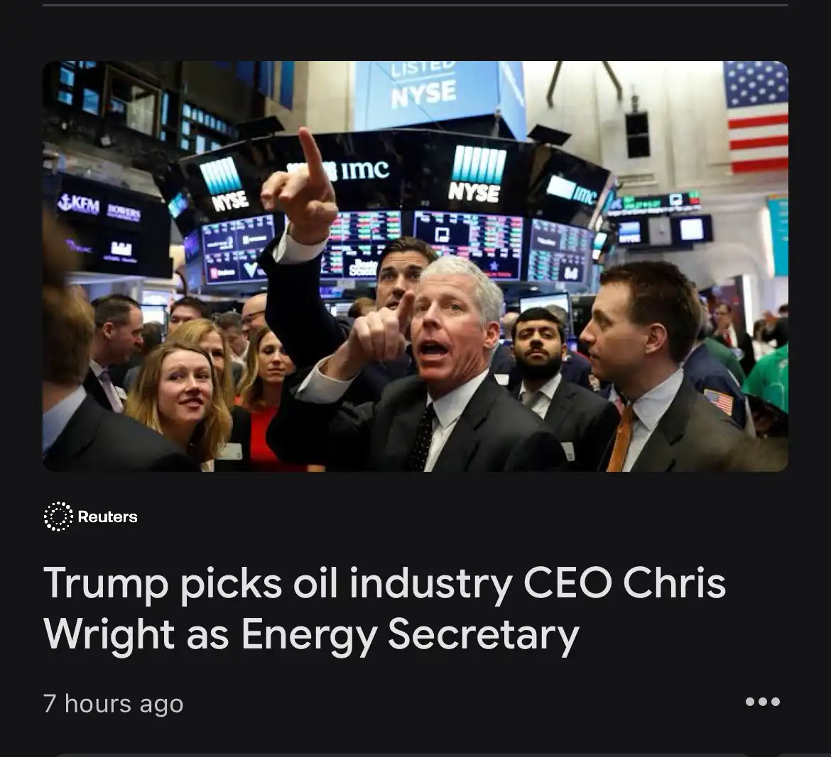 A man in a suit points emphatically upward in a crowded New York Stock Exchange trading floor, surrounded by other traders…