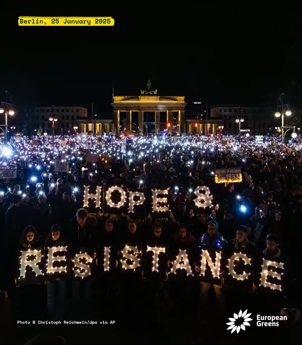 A large nighttime protest in Berlin features a crowd holding up illuminated signs spelling 'HOPE & RESISTANCE' in front of…