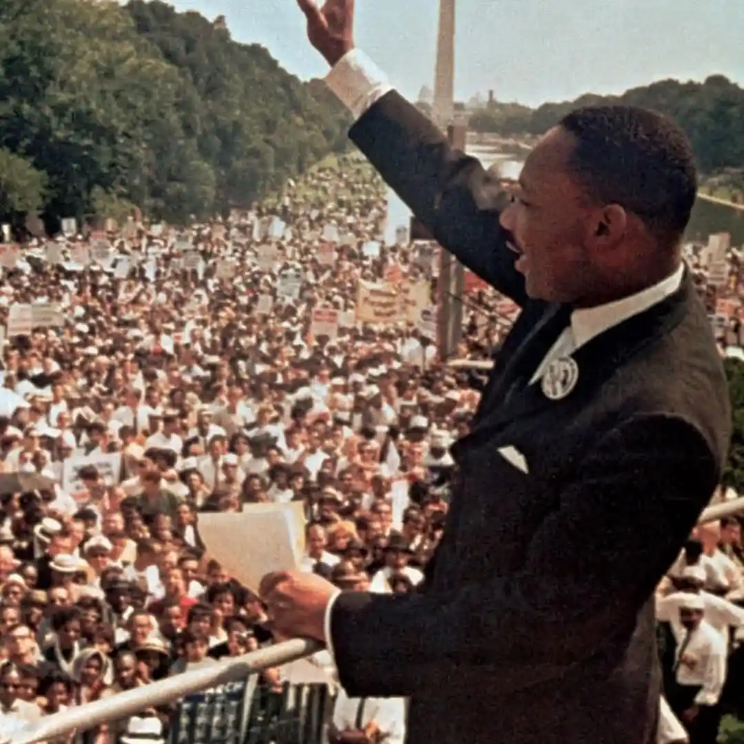 A historical photograph shows Martin Luther King Jr. speaking passionately to a massive crowd at the Lincoln Memorial, with…