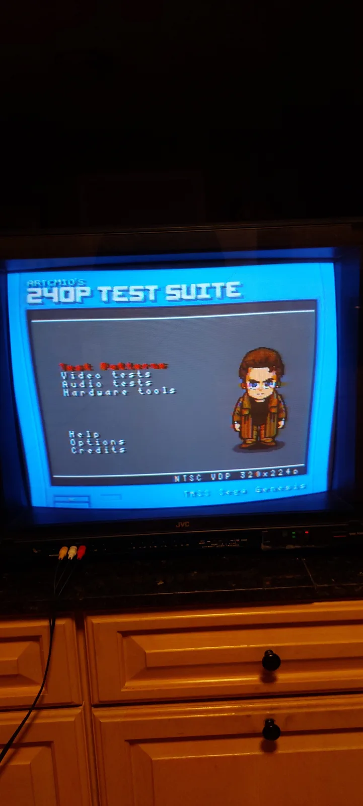 A photo of a TV displaying a retro video game test suite titled 'RITCHIE'S 240P TEST SUITE' with a pixelated character…