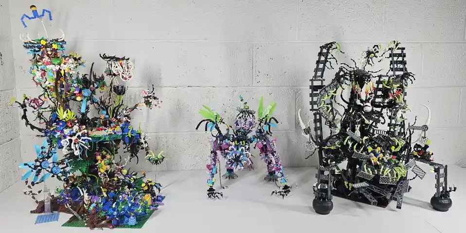 Three elaborate, asymmetrical Lego dioramas are displayed against a white cinder block wall. The left piece is a colorful…