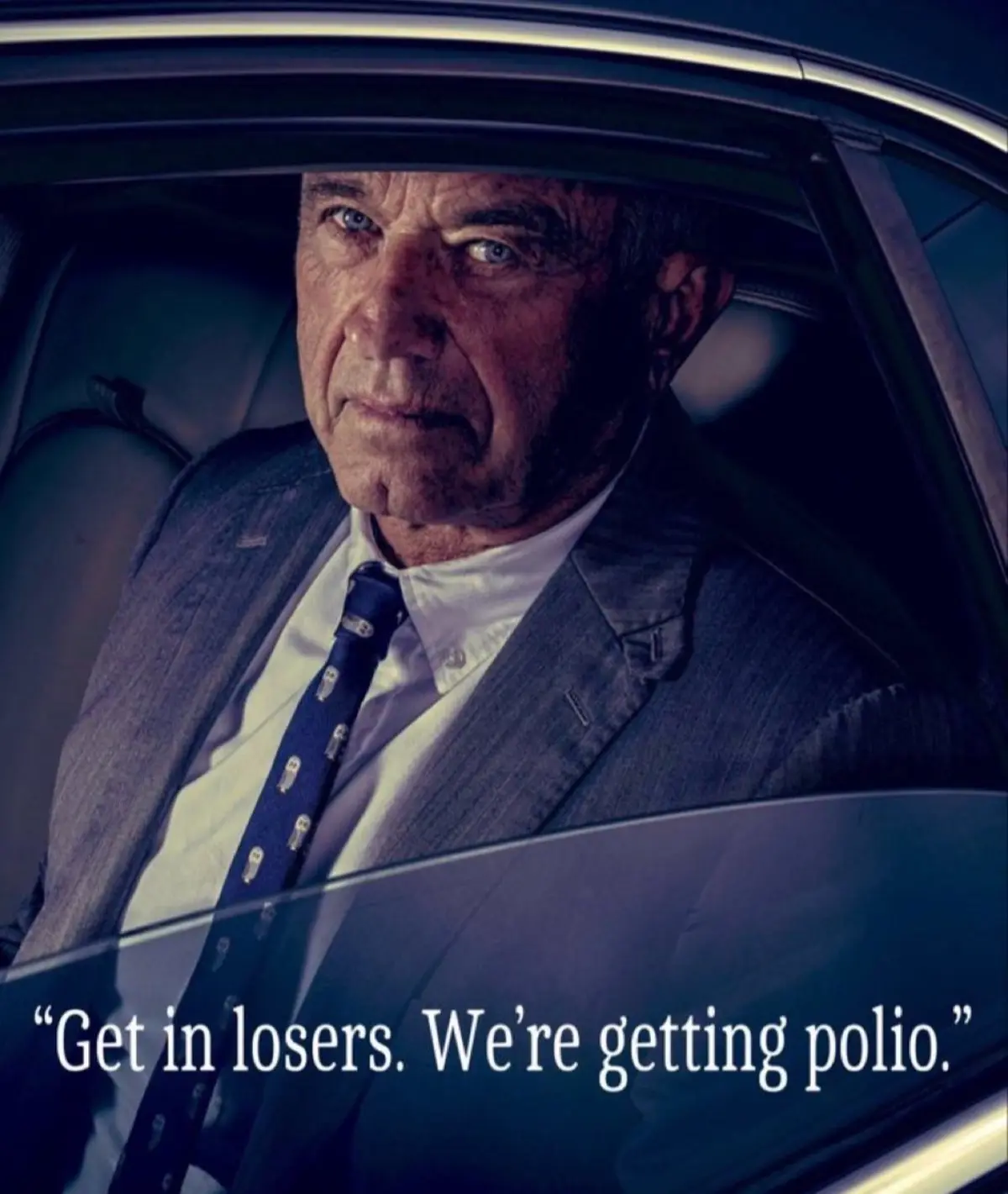An older man with a stern expression sits inside a car, wearing a suit and tie with small owl patterns. The overlaid text…