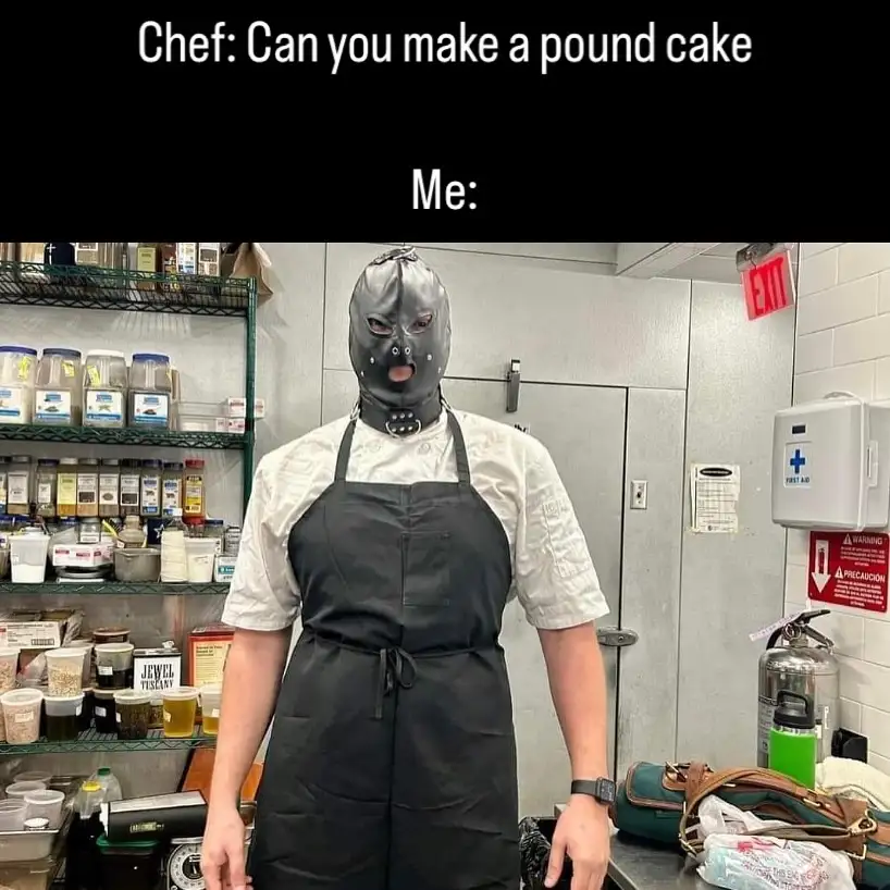 A person wearing a black chef's apron and a full-face black latex mask with a gag and eye holes stands in a commercial…