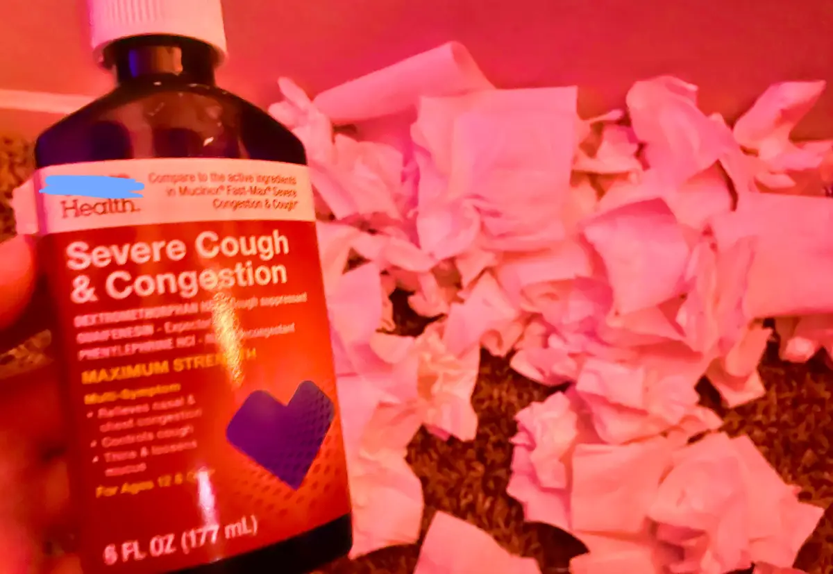 A hand holds a bottle of 'Severe Cough & Congestion' medicine labeled 'Maximum Strength' against a backdrop of a carpet…