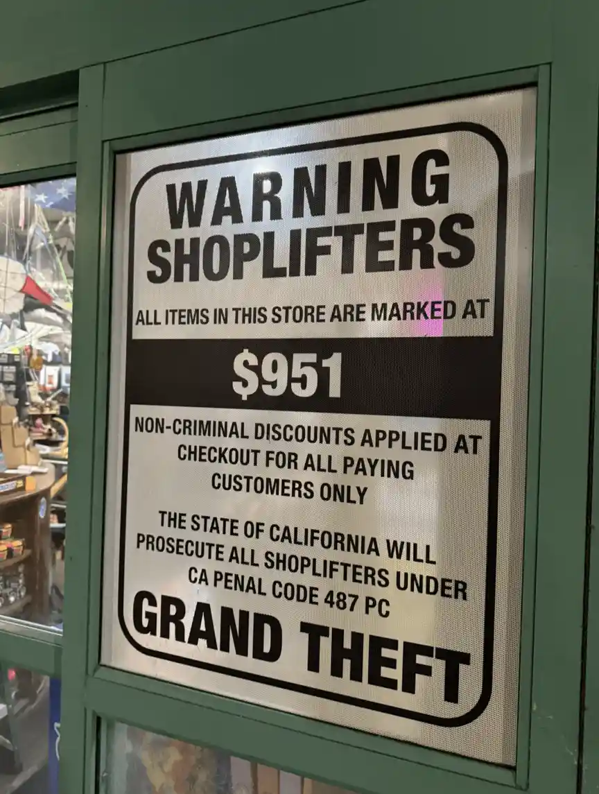 A store sign warns shoplifters that all items are marked at $951, with non-criminal discounts for paying customers, and…