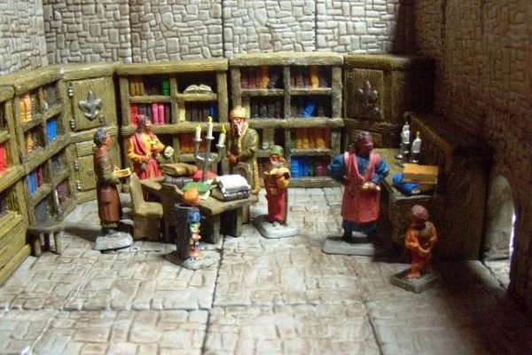 A miniature diorama depicts a medieval-style library with stone walls and floors, filled with bookshelves and small…