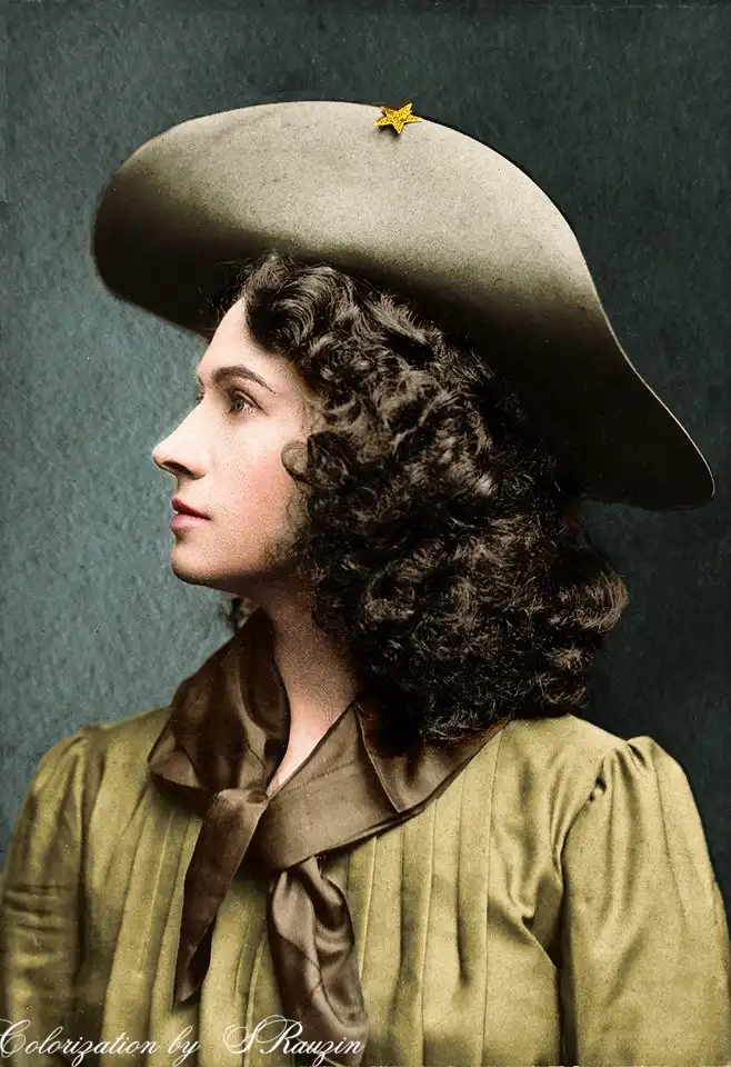 A colorized historical portrait of a woman in profile, wearing a wide-brimmed hat with a small gold star pin and a…