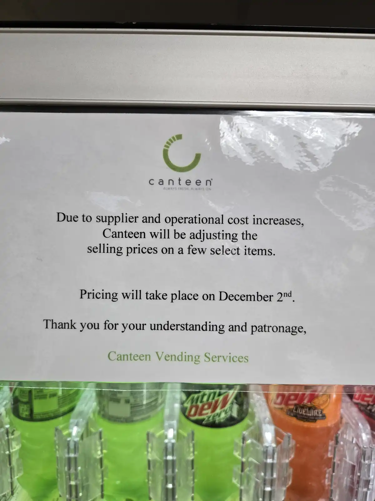 A close-up of a printed notice taped to a vending machine, announcing price increases for select items effective December…