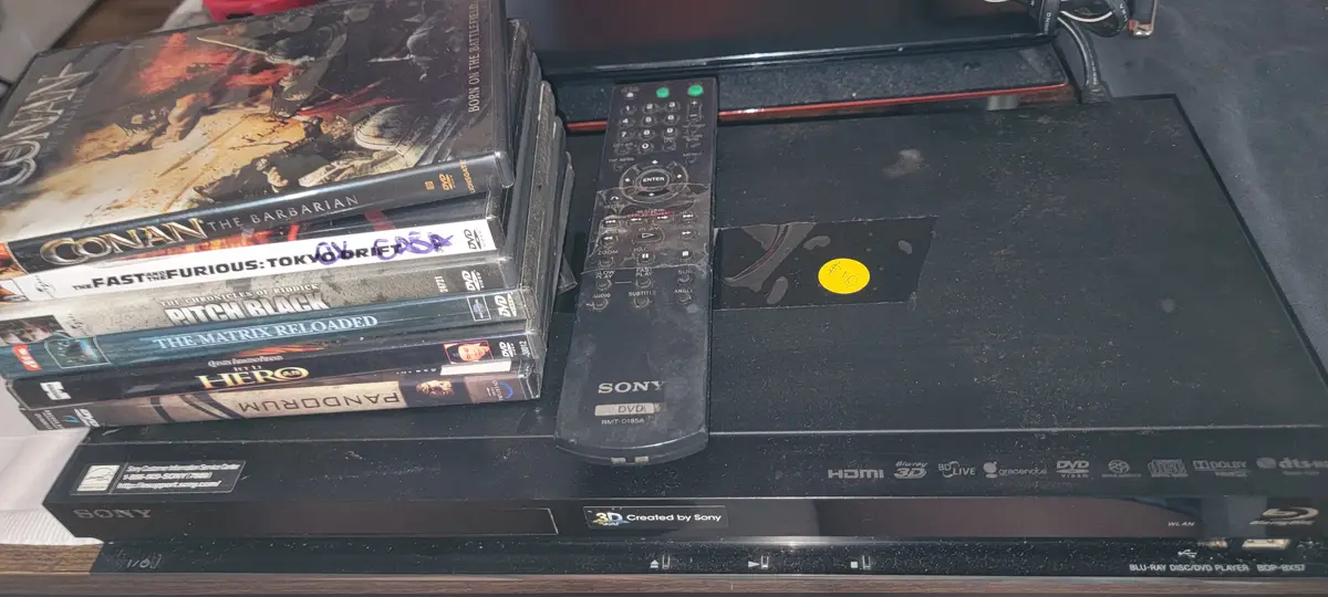 A stack of DVDs including 'Conan the Barbarian', 'The Fast and the Furious: Tokyo Drift', 'Pitch Black', 'The Matrix…