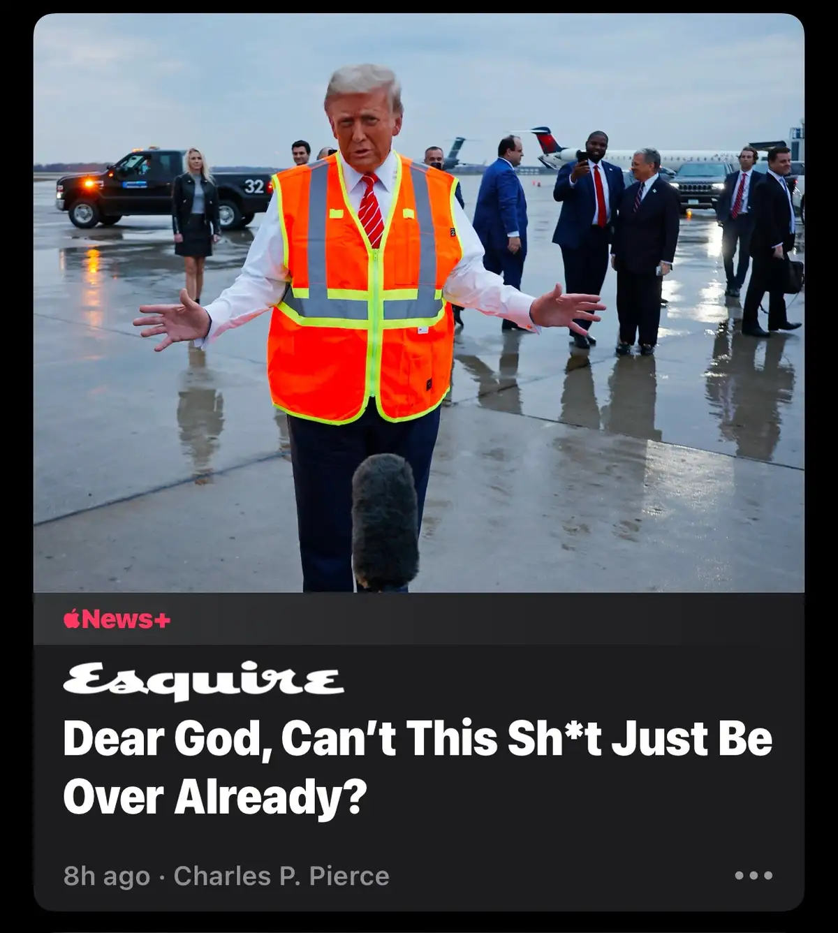 A man in an orange safety vest stands on a wet airport tarmac with arms outstretched, looking exasperated, while a…