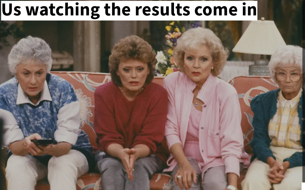 Four older women sit on a floral-patterned couch with anxious, tense expressions. The woman on the far left holds a phone…
