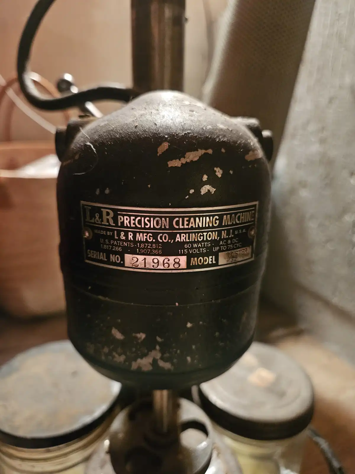 A close-up of a vintage black L&R Precision Cleaning Machine with peeling paint, showing its label with serial number 21968…