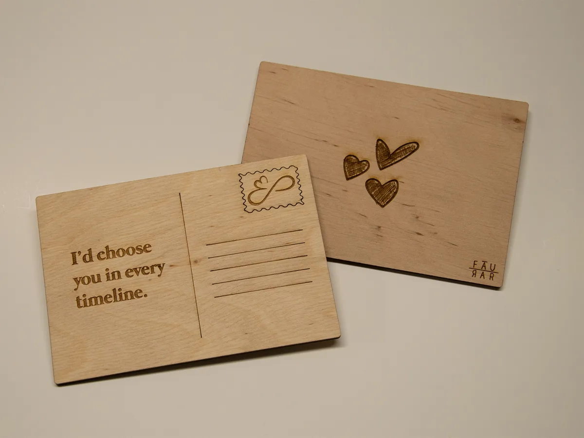 Two wooden postcards with engraved text and designs. The front card reads 'I'd choose you in every timeline.' and features a…