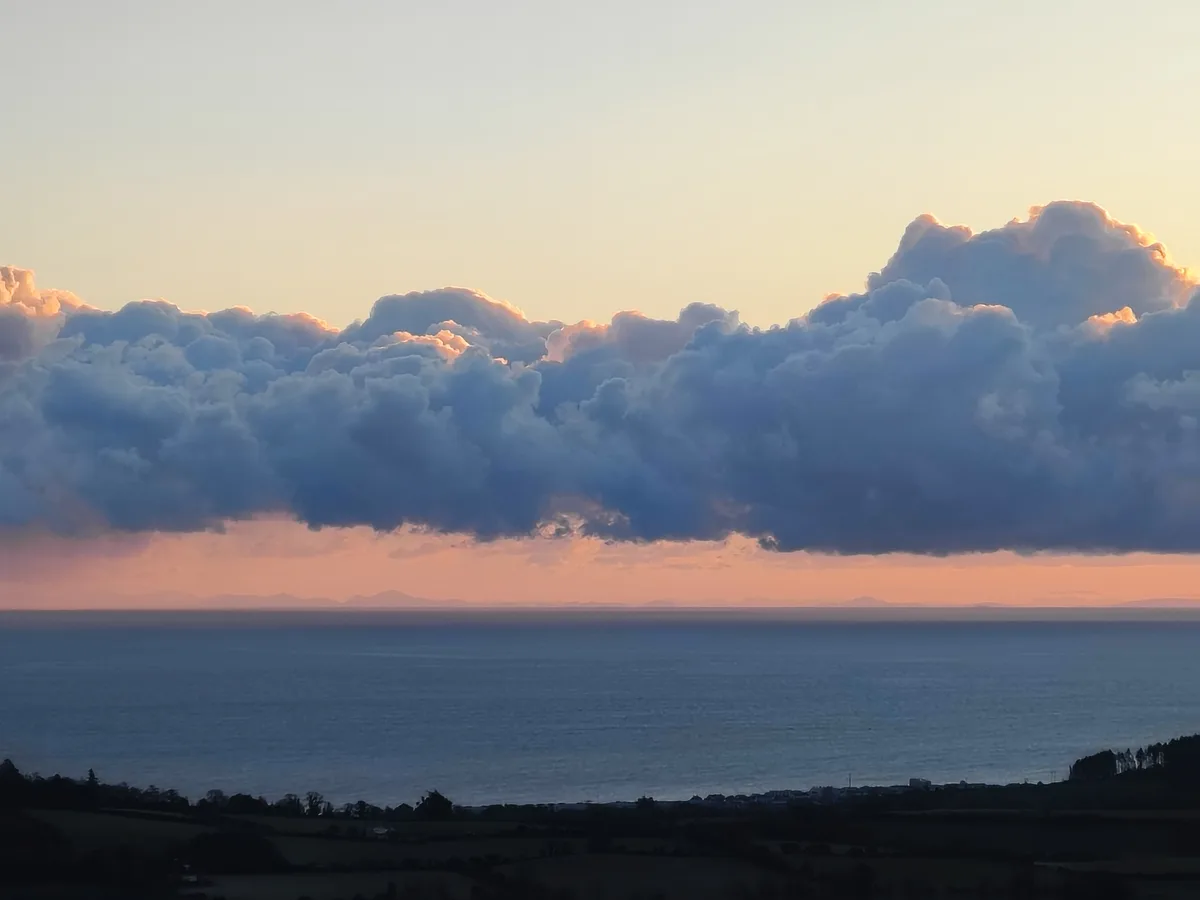 A serene landscape photo of a sunset over the ocean with dramatic clouds, overlaid with the text 'i'm not crying, you're…