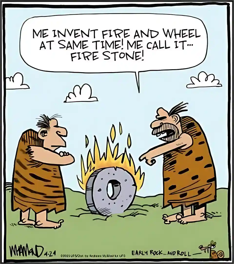Two cartoon cavemen stand in a grassy field under a blue sky with clouds. One points excitedly at a flaming stone wheel…