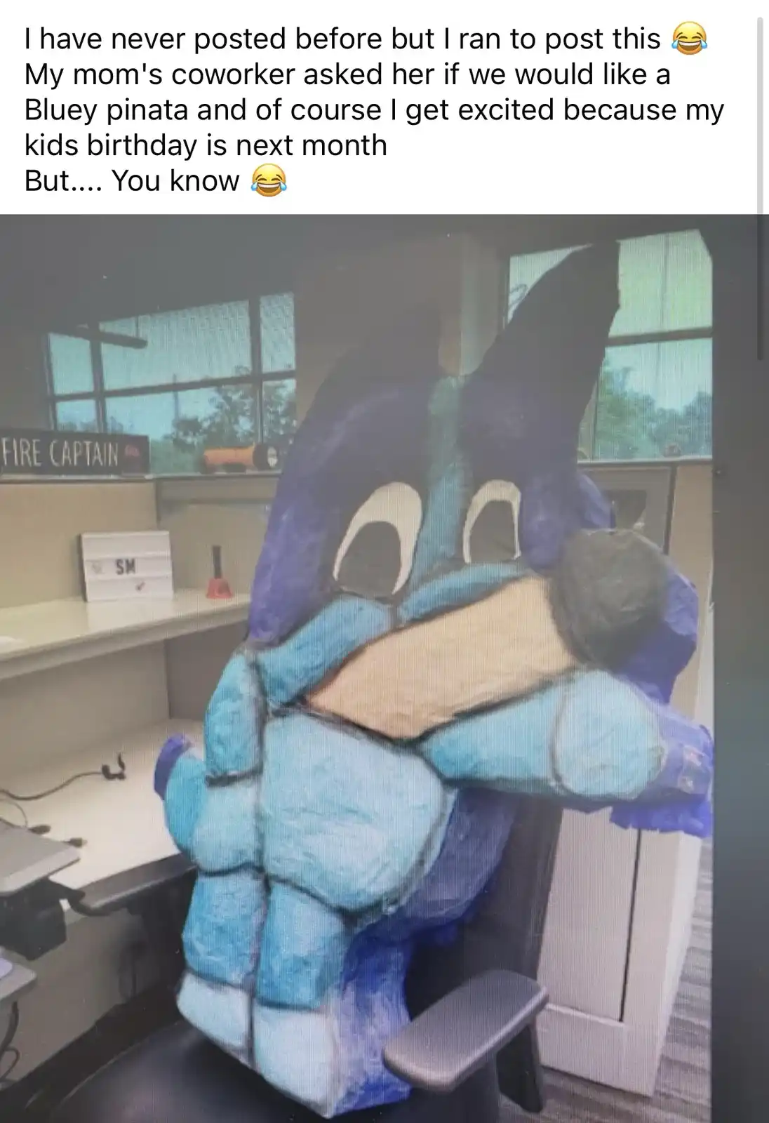 A large, handmade pinata shaped like the cartoon character Bluey sits in an office chair. The pinata is made of blue and…