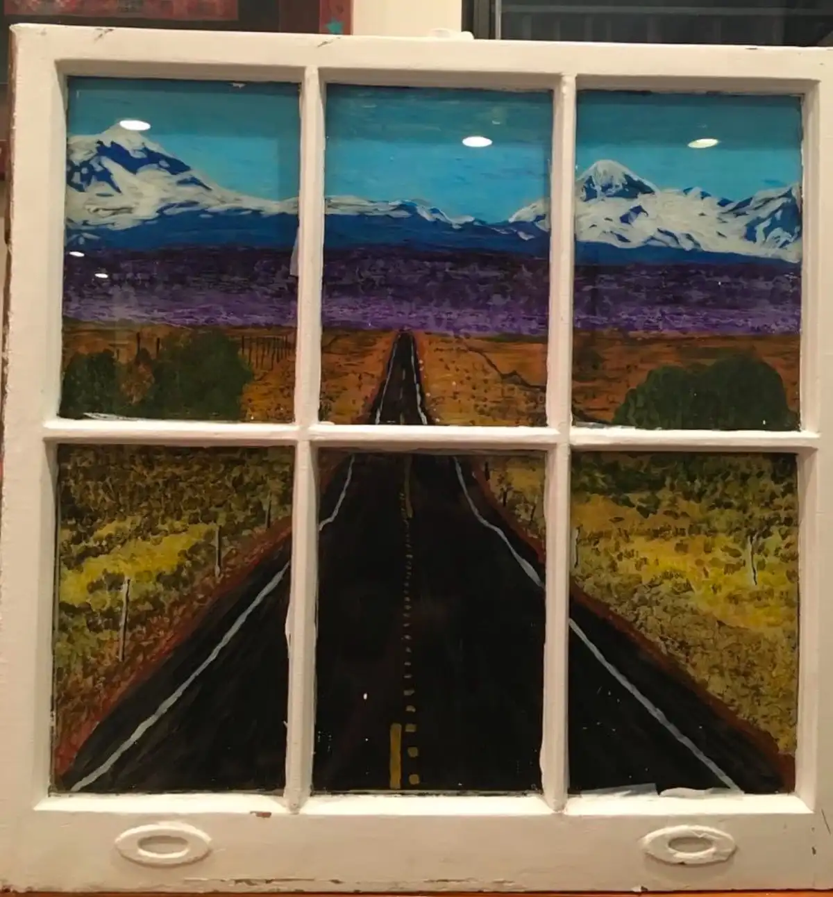 A hand-painted windowpane artwork depicts a scenic road stretching toward snow-capped mountains, divided into six panes. The…