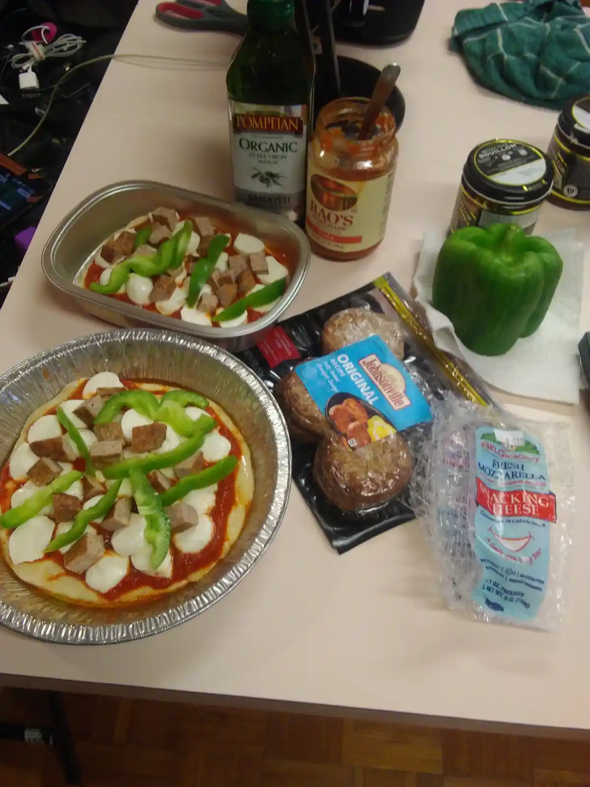 A photo shows two homemade pizzas in foil pans, topped with tomato sauce, mozzarella balls, green bell pepper strips, and…