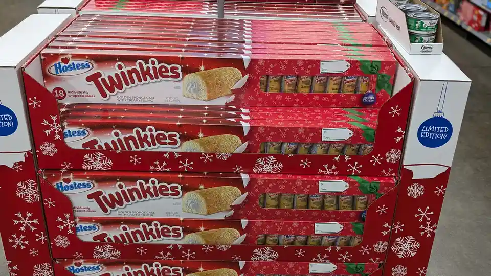 A retail display of Hostess Twinkies in red holiday-themed boxes decorated with white snowflakes and green bows, labeled as…