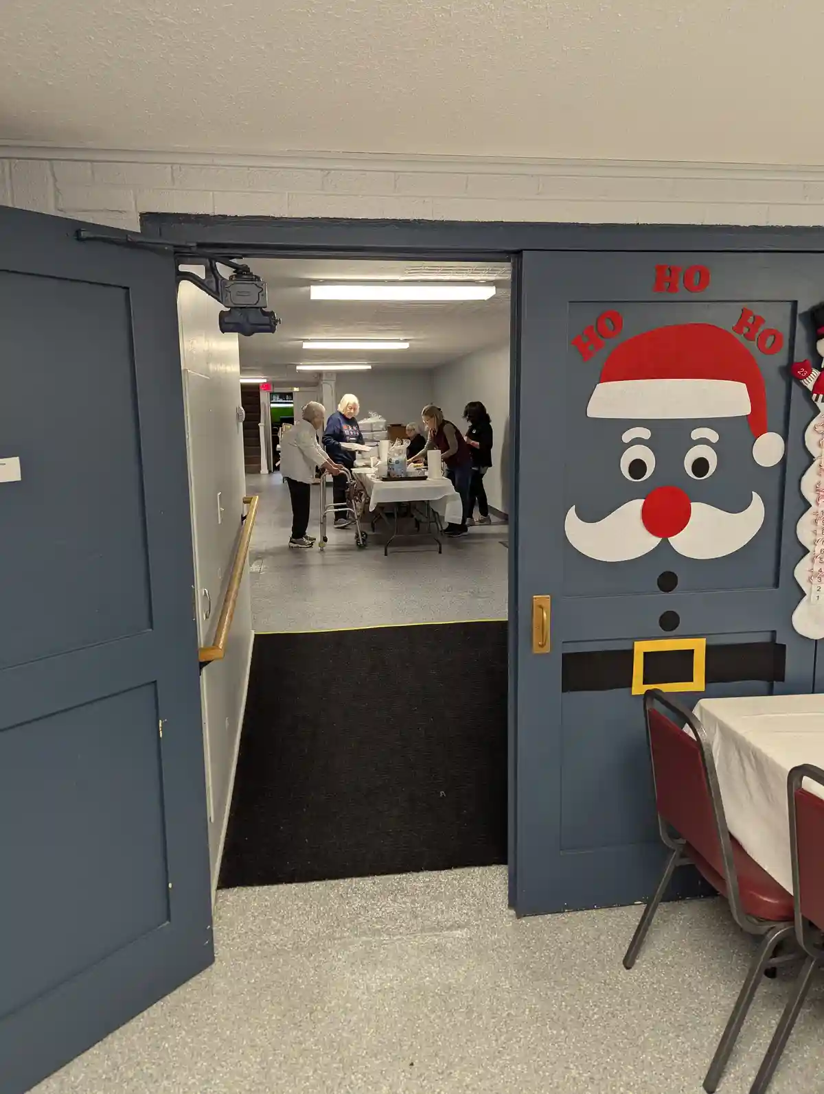 A doorway decorated with a large, cartoonish Santa Claus face on the right door, featuring a red hat, white beard, red nose…