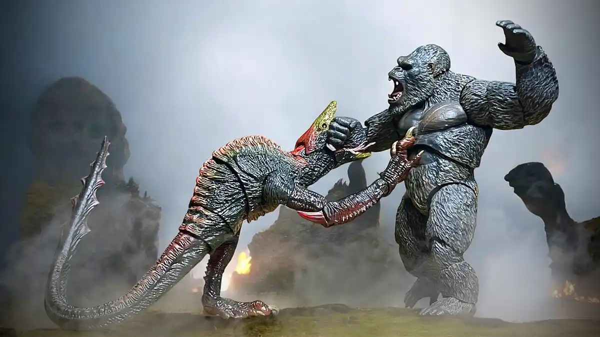 Two large monster action figures, resembling Godzilla and King Kong, are locked in a fierce physical struggle in a smoky…