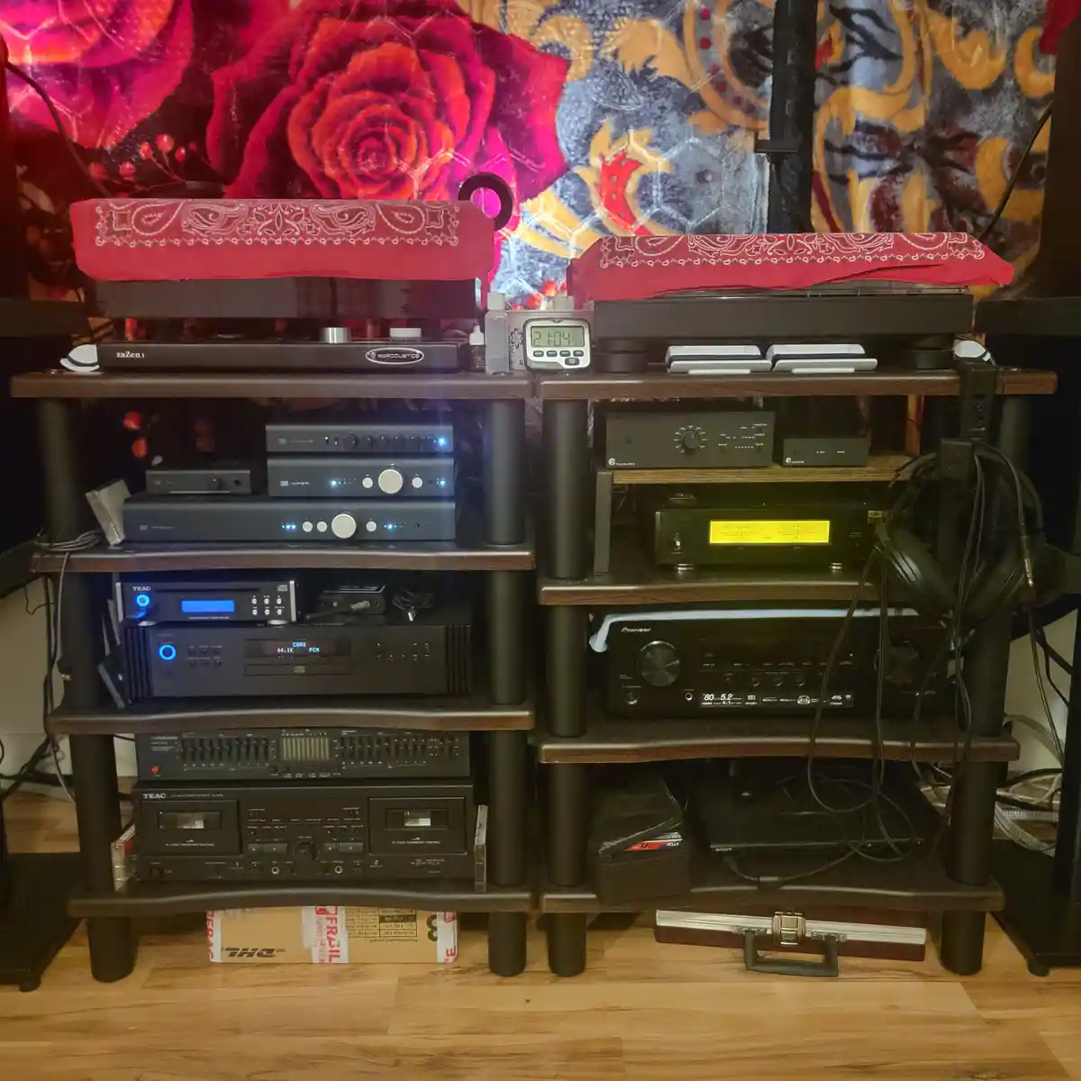 Two tall wooden shelves are packed with high-end audio equipment, including amplifiers, receivers, and turntables, all…