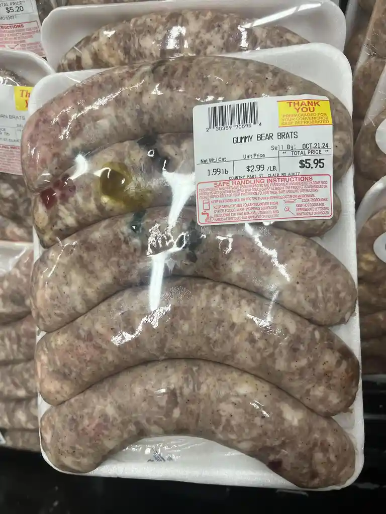 A package of raw bratwurst sausages in a store display, with a label that humorously reads 'GUMMY BEAR BRATS' instead of the…