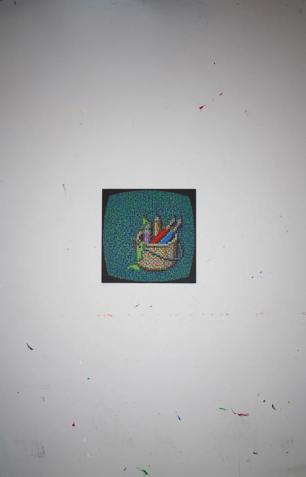 A small, pixelated image of a colorful, abstract shape resembling a crown or flame is mounted on a white wall covered in…