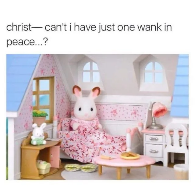 A plush white rabbit doll wearing a pink floral dress sits on a miniature bed in a dollhouse bedroom. The room has pink…