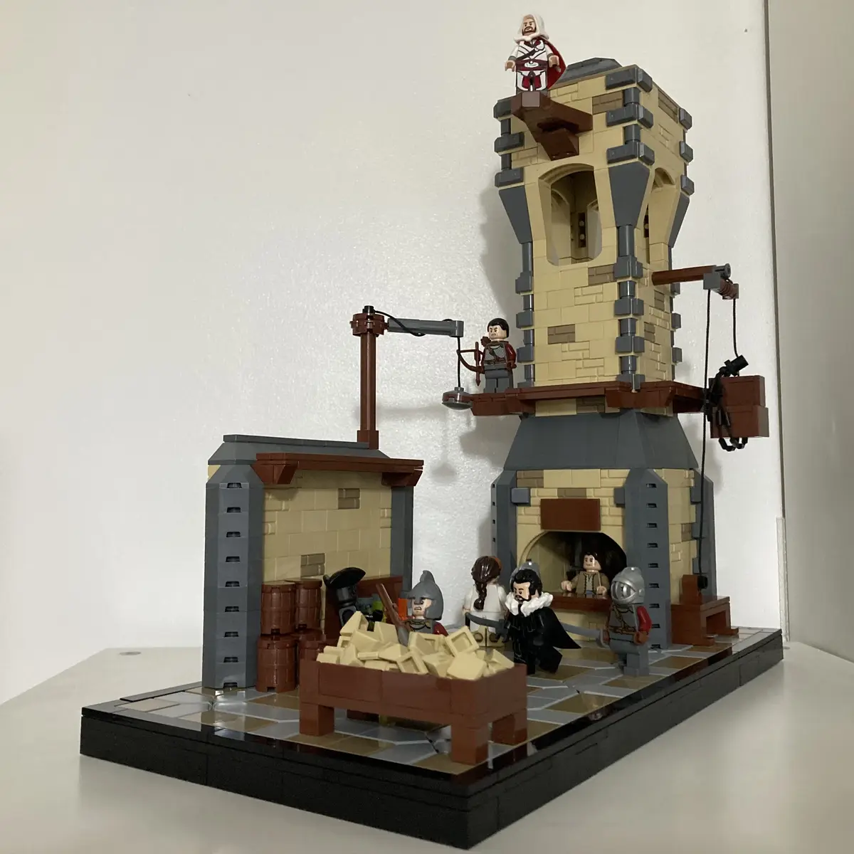 A LEGO diorama depicts a scene from Assassin's Creed, featuring a minifigure in assassin robes standing atop a tower, while…