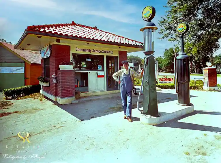 A vintage colorized photo shows a man in overalls and a cap standing confidently next to an old-fashioned gas pump at a…