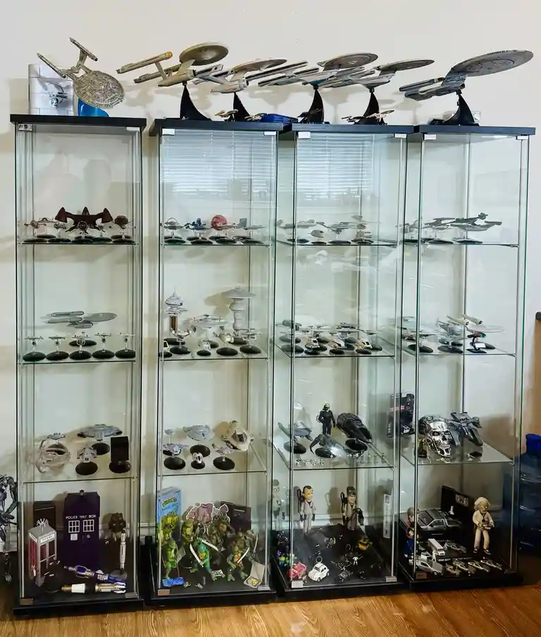 A row of tall glass display cases filled with numerous Star Trek model ships, action figures, and other pop culture…
