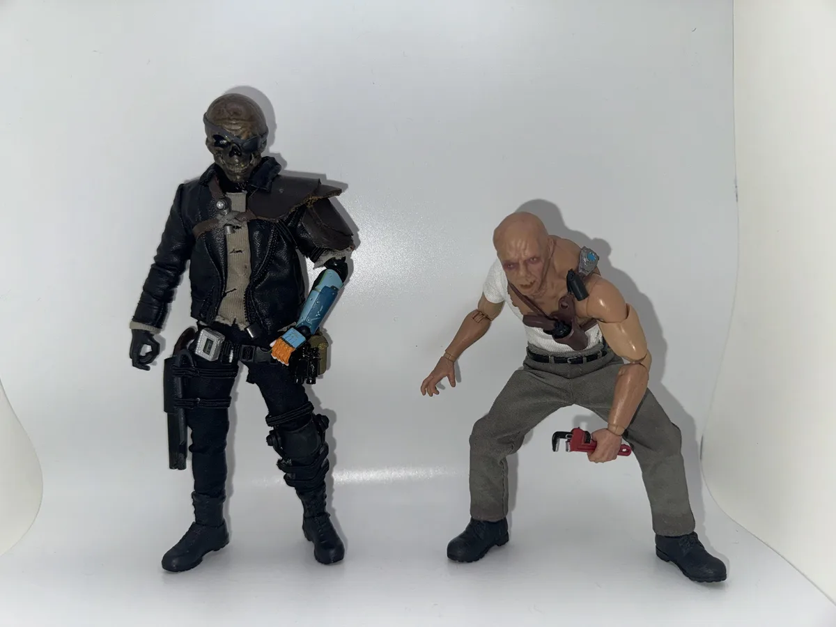 Two action figures stand against a white background. The figure on the left is a skeletal character in a black leather…