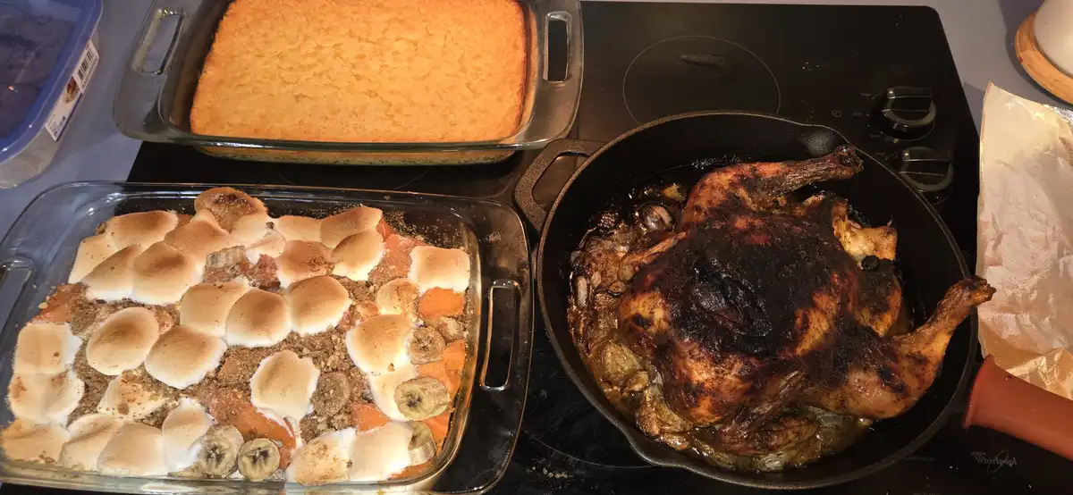 A kitchen scene shows three dishes on a stovetop: a golden-brown cornbread in a glass pan, a sweet potato casserole topped…