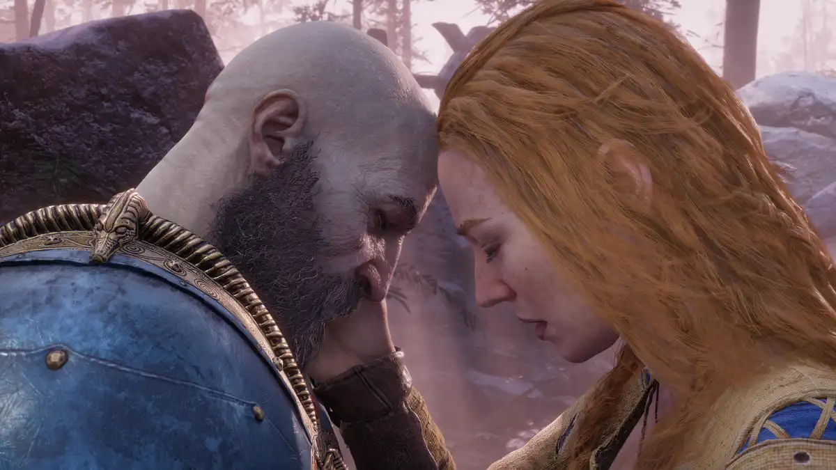 A bald man with a thick beard and blue armor is shown with his forehead touching that of a woman with long red hair, both…