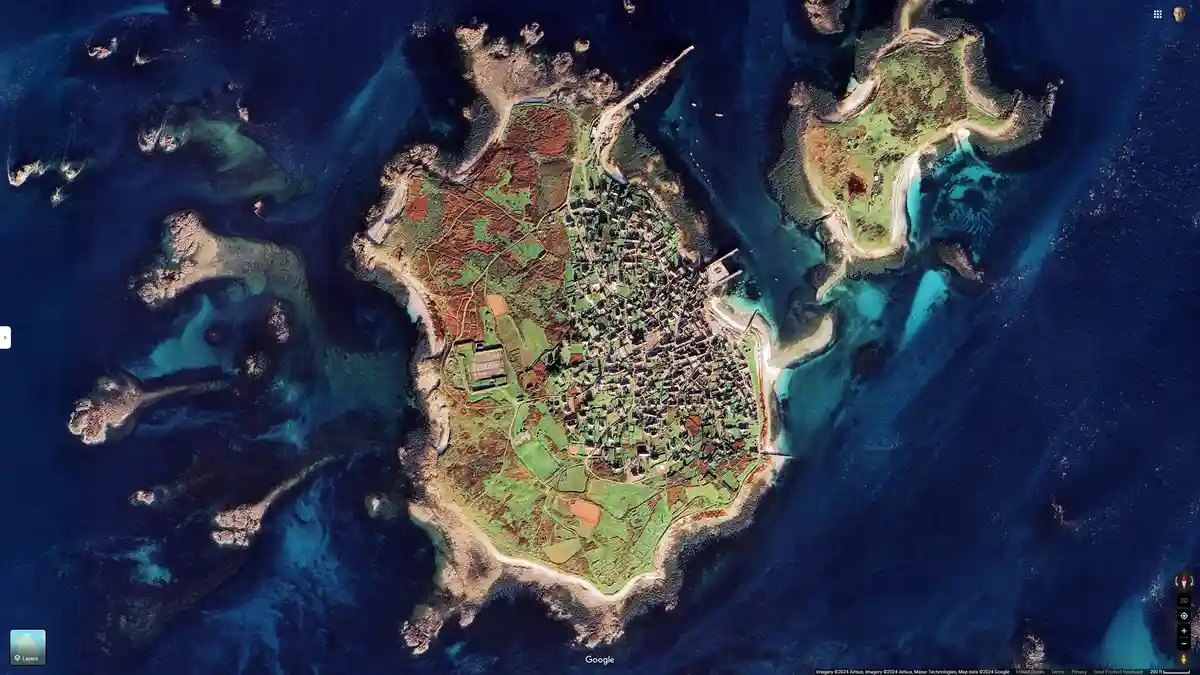 a satellite view of the island of Skye in Scotland, showing a dense town clustered in the center surrounded by green fields…