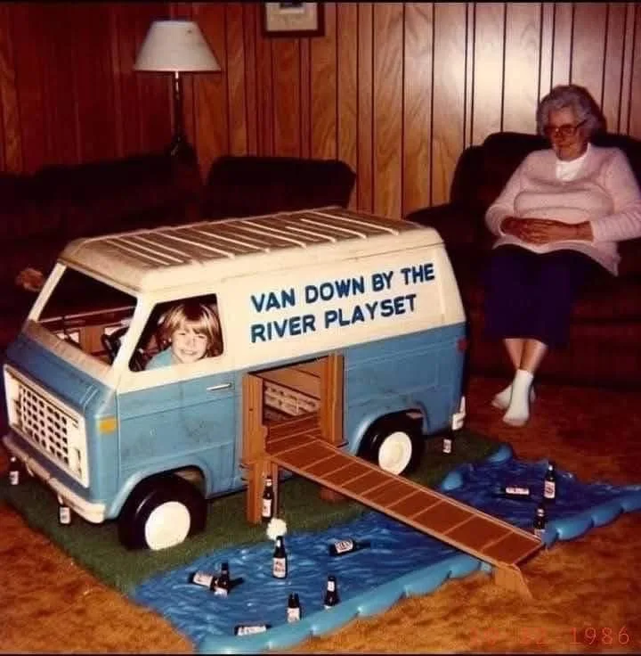 A vintage photo from 1986 shows a young child peeking from a blue and white toy van playset with a ramp leading to a blue…