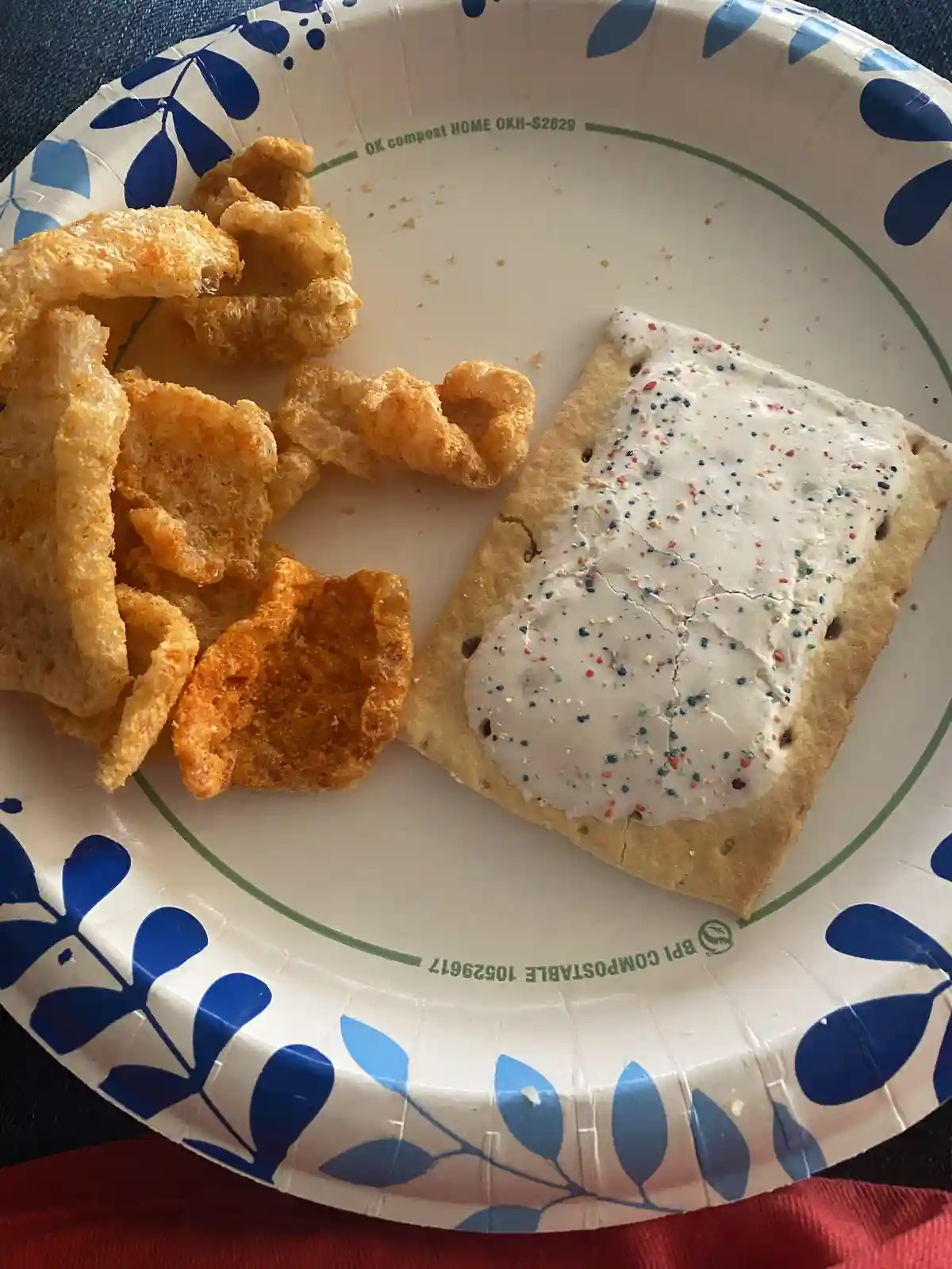A close-up photo shows a partially eaten pop tart with white frosting and colorful sprinkles on a white paper plate with…