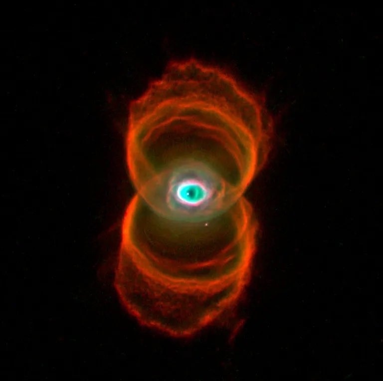 a cosmic nebula with a glowing green center and red-orange rings resembling an eye, overlaid with the text 'this is not a…
