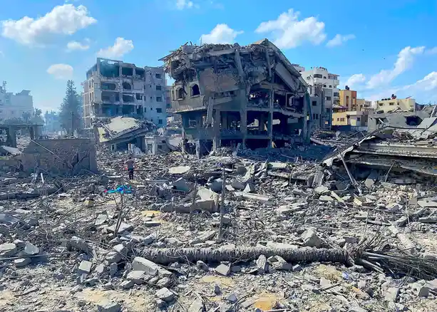 A wide shot of a cityscape devastated by destruction, with rubble-strewn streets, collapsed multi-story buildings, and a…