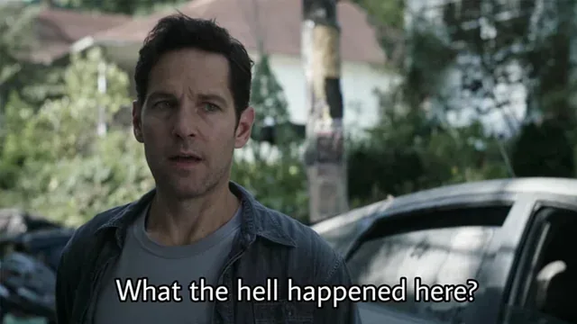 A man with dark hair and a denim jacket looks confused and shocked outdoors, with cars and trees in the background. The text…
