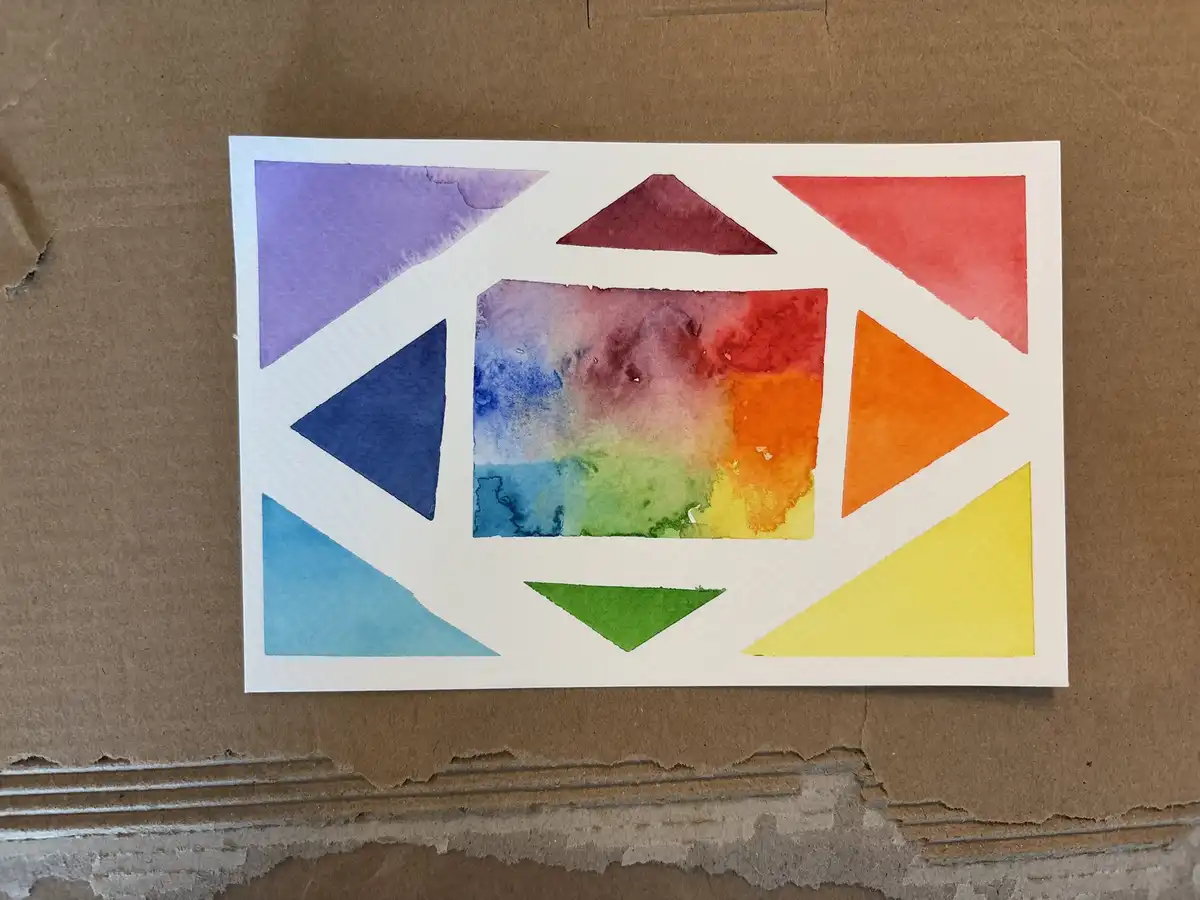 A watercolor painting on white paper shows a central rectangular area with blended rainbow colors, surrounded by eight…