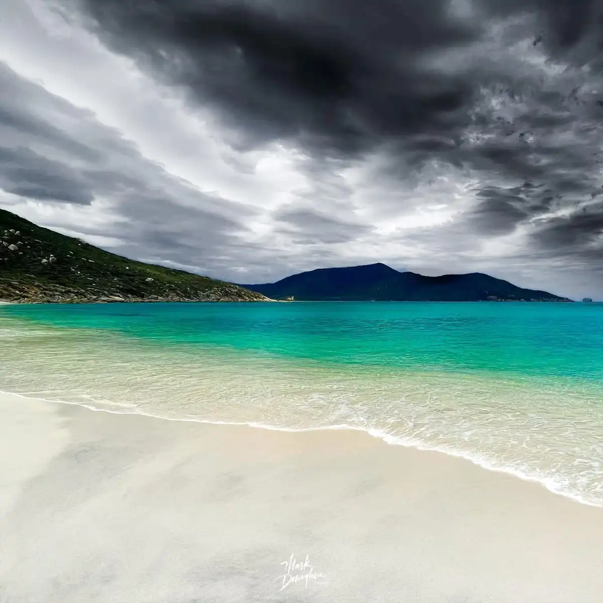 A serene beach scene with turquoise water, white sand, and dark storm clouds overhead, overlaid with the text 'I'm not…