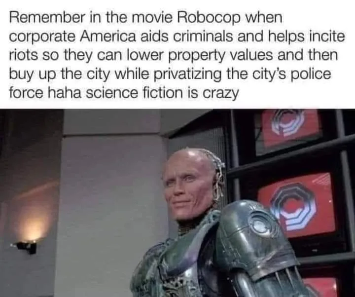 The image shows the character Robocop from the movie, with a partially robotic body and a human face, looking slightly to…